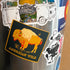 American Wild Bison sticker on metal pole surrounded by other stickers. 